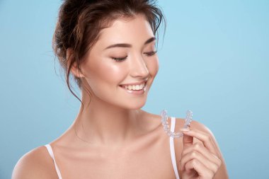 young attractive woman with bare shoulders and dental tray on blue background