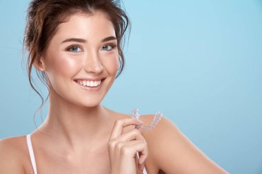 young attractive woman with bare shoulders and dental tray on blue background