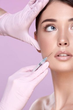 şırınga ve pembe arka plan üzerinde genç esmer kadın ile lastik eldiven kozmetolojist kısmi görünümü