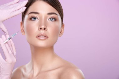 şırınga ve pembe arka plan üzerinde genç esmer kadın ile lastik eldiven kozmetolojist kısmi görünümü