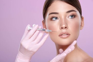 şırınga ve pembe arka plan üzerinde genç esmer kadın ile lastik eldiven kozmetolojist kısmi görünümü