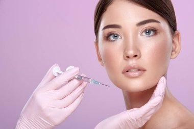 şırınga ve pembe arka plan üzerinde genç esmer kadın ile lastik eldiven kozmetolojist kısmi görünümü