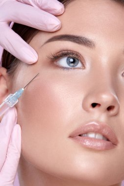 şırınga ve pembe arka plan üzerinde genç esmer kadın ile lastik eldiven kozmetolojist kısmi görünümü