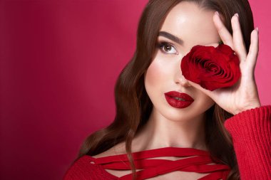 kırmızı arka plan üzerinde akşam makyaj ve kırmızı gül ile çekici genç kadın