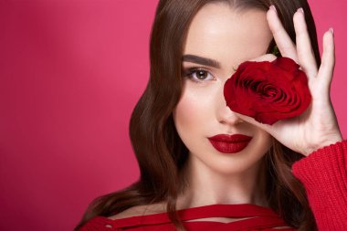 kırmızı arka plan üzerinde akşam makyaj ve kırmızı gül ile çekici genç kadın