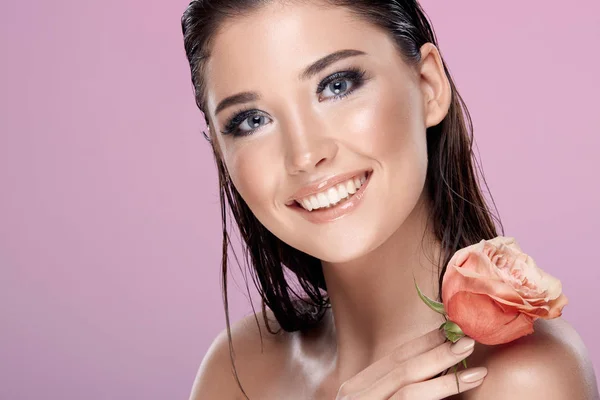 portrait of attractive woman with rose on pink backdrop