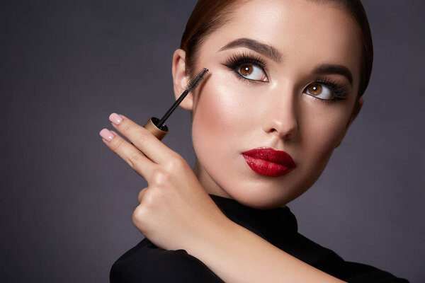 attractive young woman with evening makeup and mascara on dark background