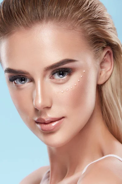 mavi zemin üzerinde yüzünde krem ile güzel genç kadın