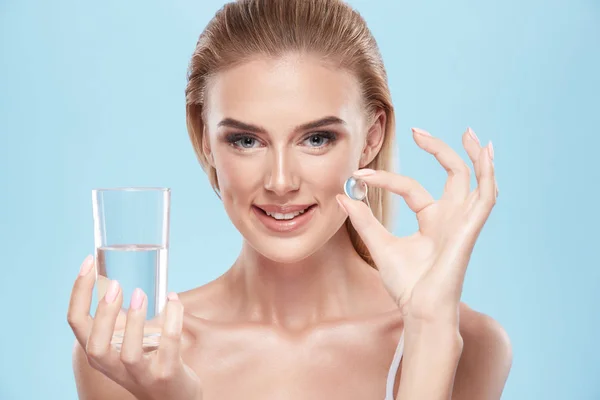 Joven Rubia Chica Mostrando Píldora Mano Vaso Agua Azul — Foto de Stock