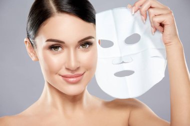 gri arka planda yüzünde yüz maskesi ile genç kadın portresi