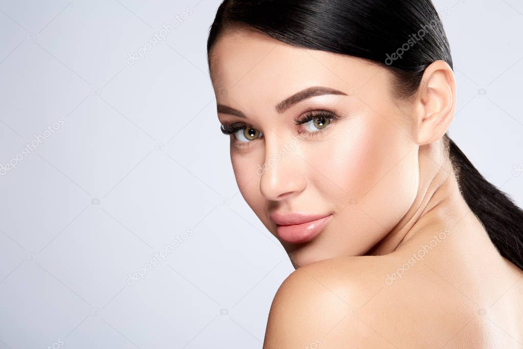 portrait of young woman with nude makeup on face on grey background