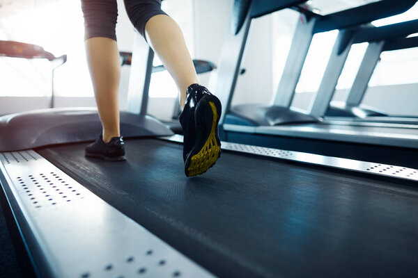 partial view of woman exercising on treadmill in gym