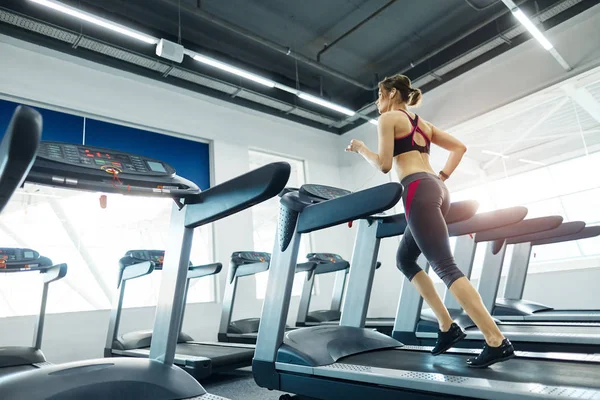 在体育馆的跑步机上锻炼的年轻健康女子 — 图库照片
