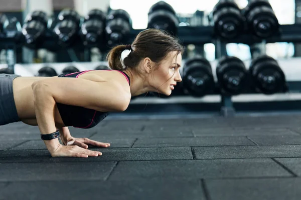 athletic sportswoman training in gym alone
