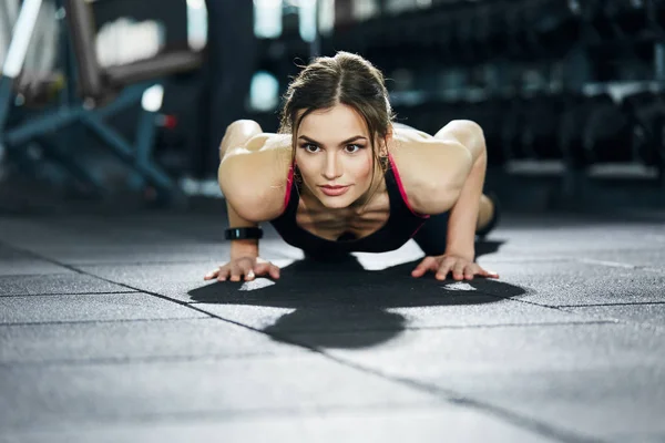 athletic sportswoman training in gym alone
