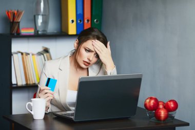 young businesswoman with credit card sitting at workplace with laptop