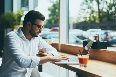 young handsome businessman with eyeglasses working in cafe