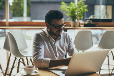 young handsome businessman with eyeglasses working in cafe
