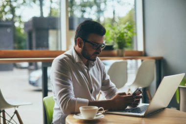 young handsome businessman with eyeglasses working in cafe