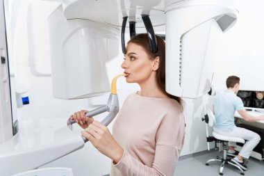 diş kliniğinde genç kadın hastanın dişlerini köryor diş hekimi