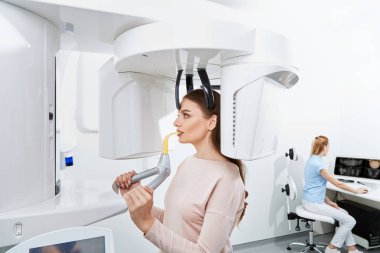 diş kliniğinde genç kadın hastanın dişlerini köryor diş hekimi