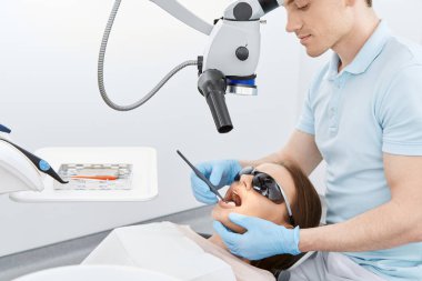 diş kliniğinde genç kadın hastanın dişlerini köryor diş hekimi