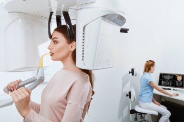 diş kliniğinde genç kadın hastanın dişlerini köryor diş hekimi