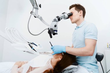 diş kliniğinde genç kadın hastanın dişlerini köryor diş hekimi