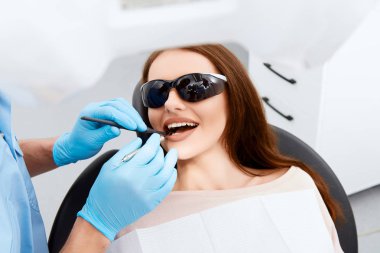 diş kliniğinde genç kadın hastanın dişlerini köryor diş hekimi