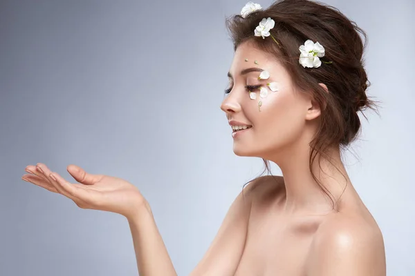 灰色の背景にポーズ顔に花を持つ美しい柔らかい女性 — ストック写真