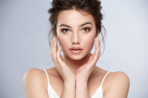 lovely girl with dark eyes and light make-up holding her arms near face