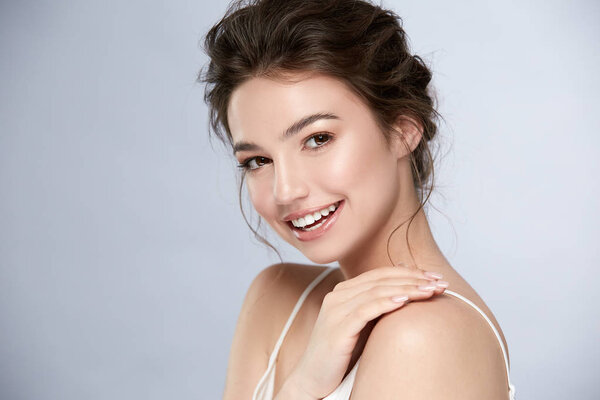 beautiful woman with shiny smile and light make-up looking to camera