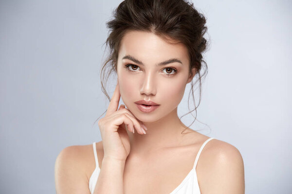 girl with strong view and light mua looking to camera and touching her cheek