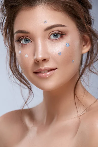 Porträtt av vacker flicka med färska blå blommor på hennes ansikte — Stockfoto