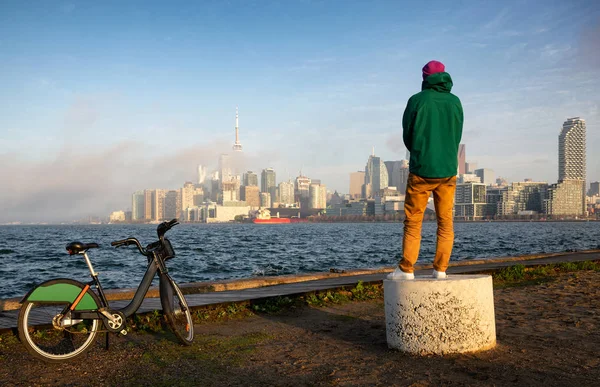 Bisikletli adam Ontario Rıhtım Gölü ve Toronto şehir panoraması üzerinde gün batımını izliyor