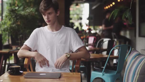 Young man surfing webbplats och chatta, frilansare och bloggare som arbetar som grafisk formgivare inomhus, modern arbetsplats sitter i kaféet. Öppen laptop i restaurang. — Stockvideo