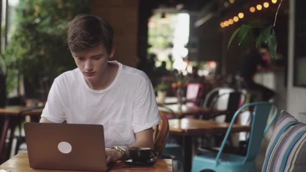 Ung man Slutför arbete, frilansare och bloggare som arbetar som grafisk formgivare inomhus, modern arbetsplats sitter i Café. Öppen laptop i restaurang. — Stockvideo