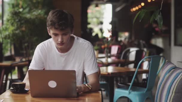 Young man surfing webbplats och chatta, frilansare och bloggare som arbetar som grafisk formgivare inomhus, modern arbetsplats sitter i kaféet. Öppen laptop i restaurang. — Stockvideo