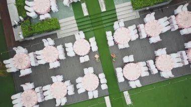 Drone düğün akşam yemeği dekorasyon üzerinde uçan, ya da evlilik yıldönümü, bahçede açık, sandalyeler ve masalar ayarlama Catering, havadan görünüm. Tropikal dekor tarzı atmosfer.