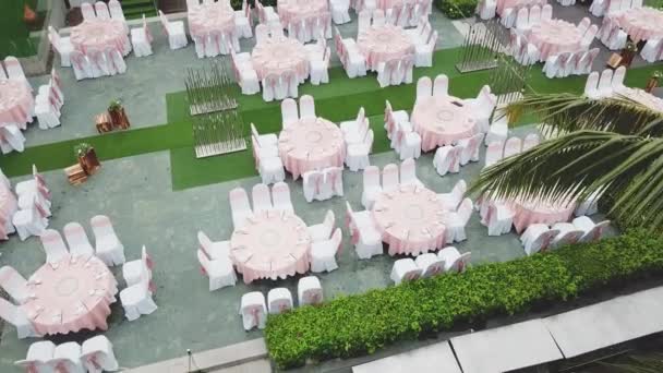 Drone flying over wedding dinner decoration, or marriage anniversary, in the garden outdoor, catering setting chairs and tables, aerial view. Tropical decor style atmosphere. — Stock Video