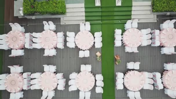 Drone volando sobre la decoración de la cena de boda, o aniversario de matrimonio, en el jardín al aire libre, sillas y mesas de catering, vista aérea. Ambiente de decoración tropical . — Vídeos de Stock