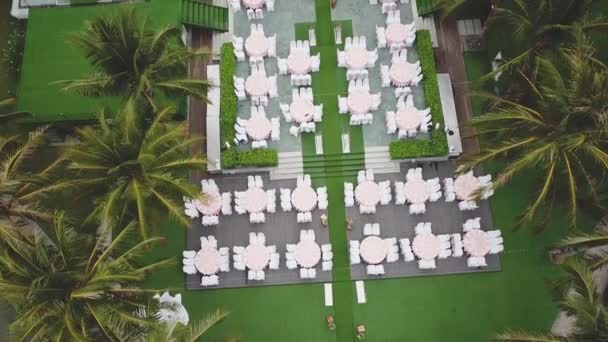 Drone survolant la décoration du dîner de mariage, ou anniversaire de mariage, dans le jardin en plein air, chaises et tables de restauration, vue aérienne. Ambiance de style décor tropical . — Video