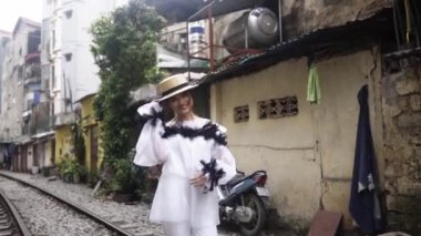 Eski binalar arasında demiryolu ile Asya sokak boyunca yürüyüş güzel ve genç moda Mestizo kız. Vietnam turist destinasyonu yolculuk kavramı. Beyaz moda elbise sevimli kadın.