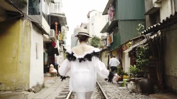 Tillbaka Följ vyn till den vackra och unga mode flickan går längs den asiatiska gatan med järnväg mellan gamla byggnader. Journey Concept i vietnamesiska turistmål i Hanoi. — Stockvideo