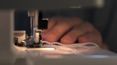 Bir dikiş makinesi üzerinde çalışan adam