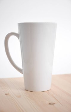 Beyaz arka plan üzerinde ahşap masa üzerinde beyaz yüksek kupa