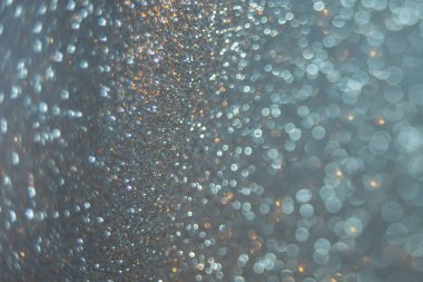 Close-up abstract unfocused background shiny texture photo glitter in a Golden-blue hue. Selective focus with bokeh light.