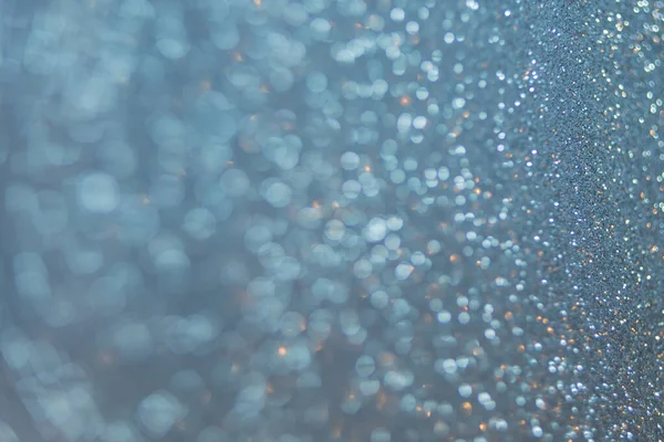 Close-up abstract unfocused background shiny texture photo glitter in a Golden-blue hue. Selective focus with bokeh light.