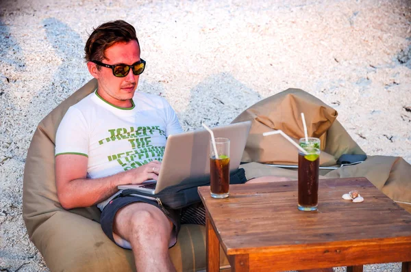 Plajda çalışan adam. Kumun üzerinde çalışan adam. Laptop ile çalışan adam. Adam sahilde dizüstü bilgisayar ile.