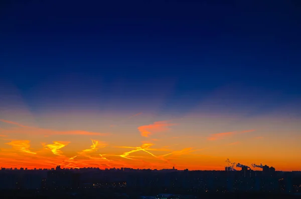 Nuvens laranja com trilhas de aeronaves fundo do céu e luz da cidade meia-noite à noite — Fotografia de Stock